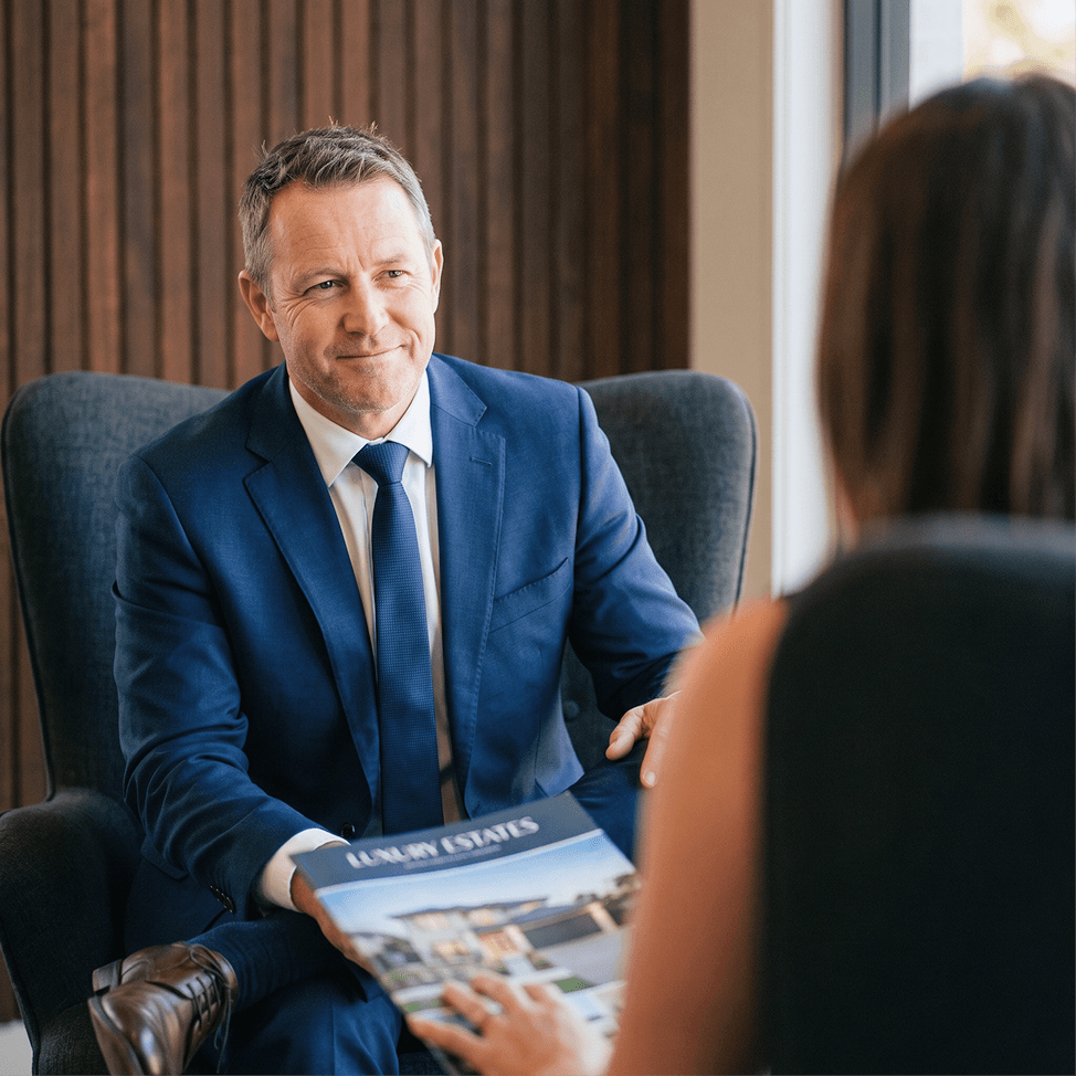 A BlueRibbon agent presenting a property brochure to a client